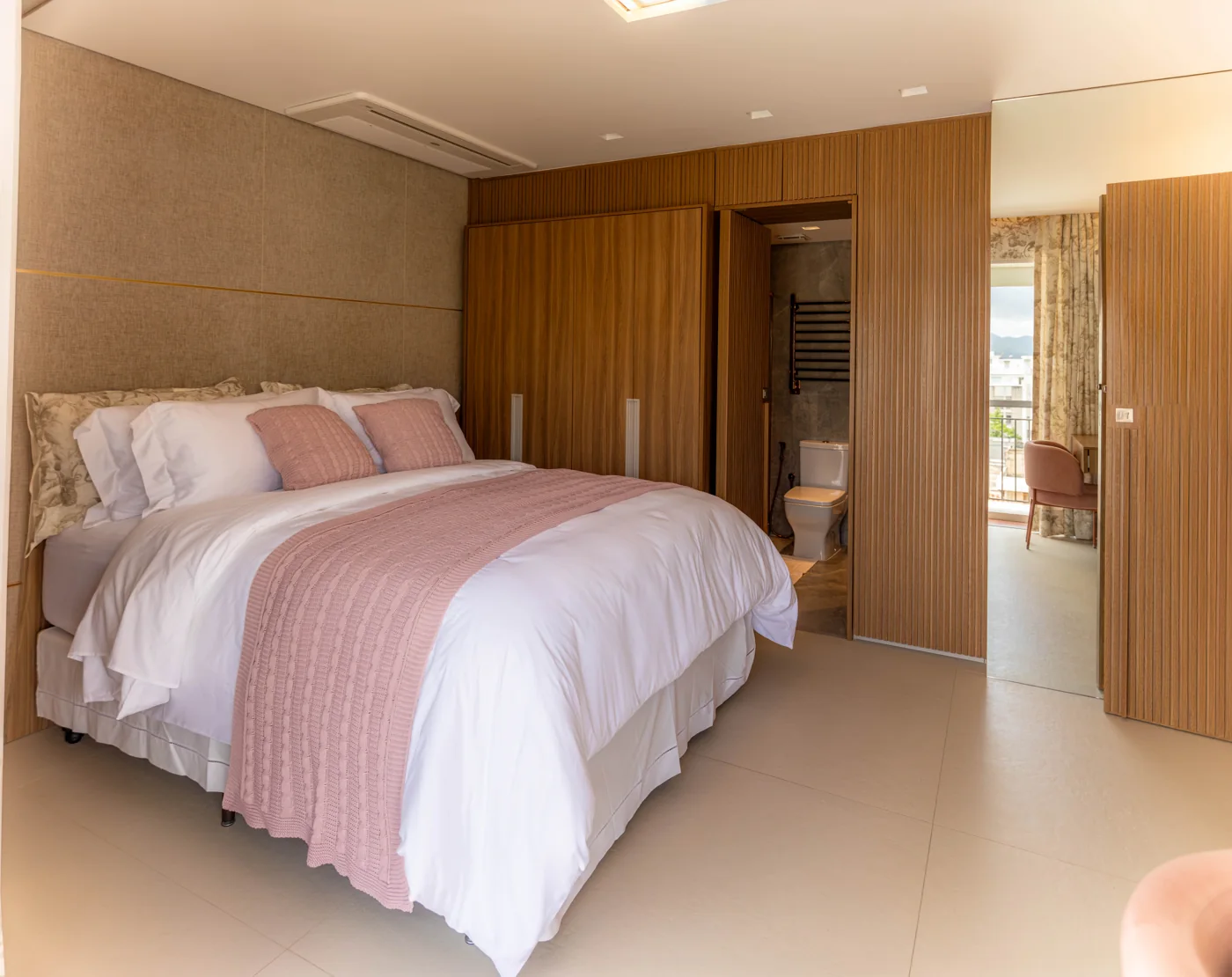 Quarto do apartamento com roupa de cama rosa