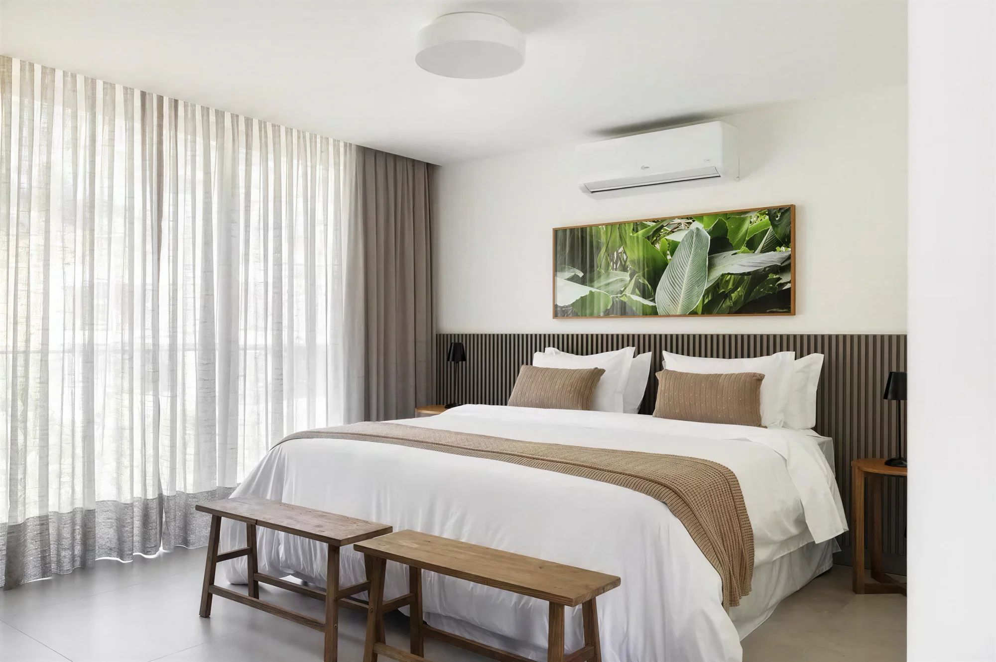 Quarto da casa com roupa de cama clara e banco de madeira