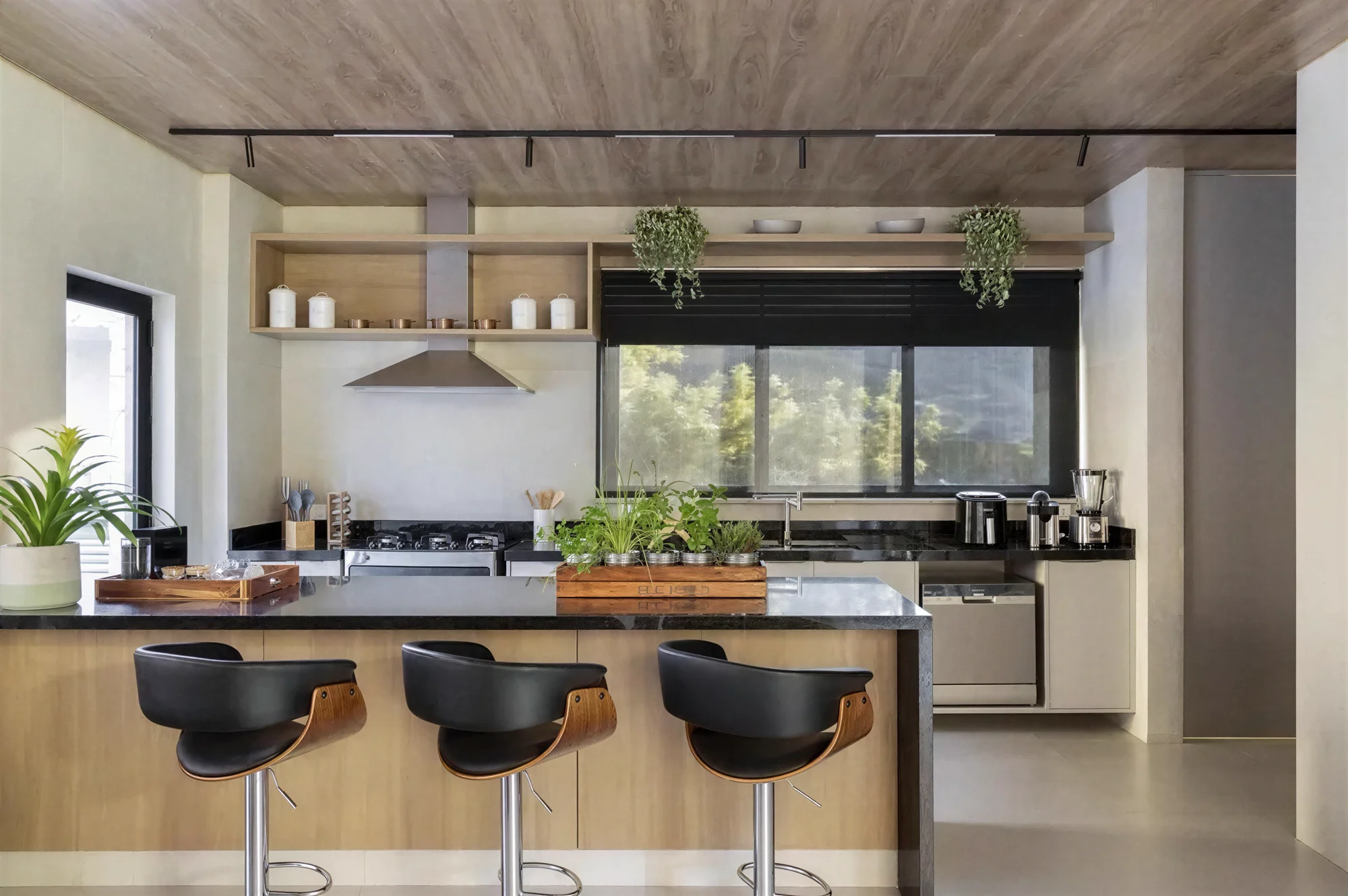 Cozinha com bancada de pedra escura e banquetas